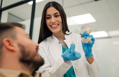 Dentist showing dental implant to patient in modern clinic