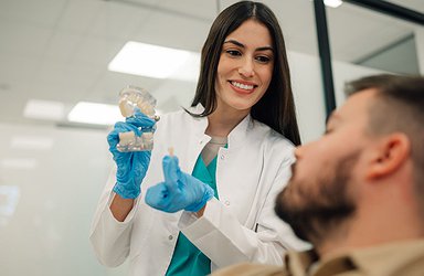 dentist-showing-dental-implant-to-patient