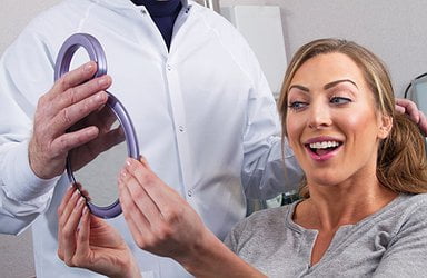 woman-checks-her-cosmetic-dentistry-procedure-in-mirrow