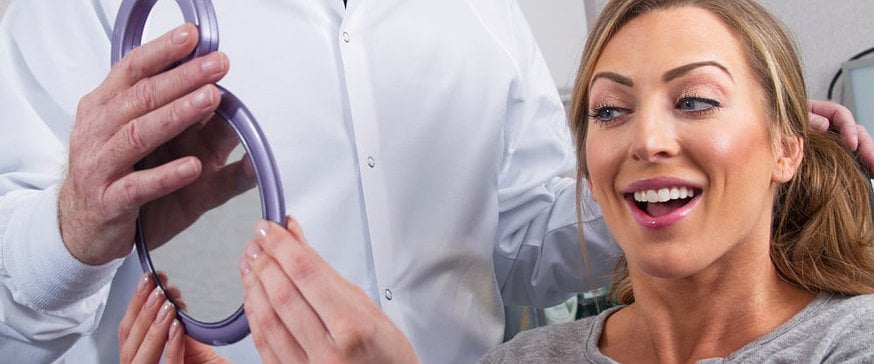 woman-checks-her-cosmetic-dentistry-procedure-in-mirrow
